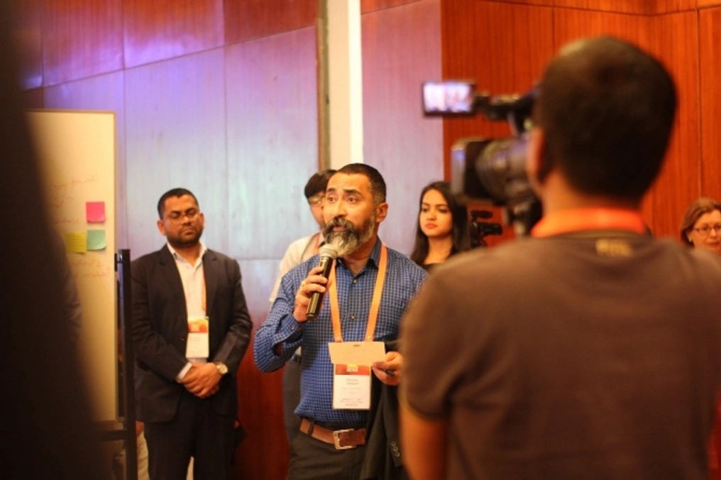 Adhikari speaks as a crowd watches and films him speaking.