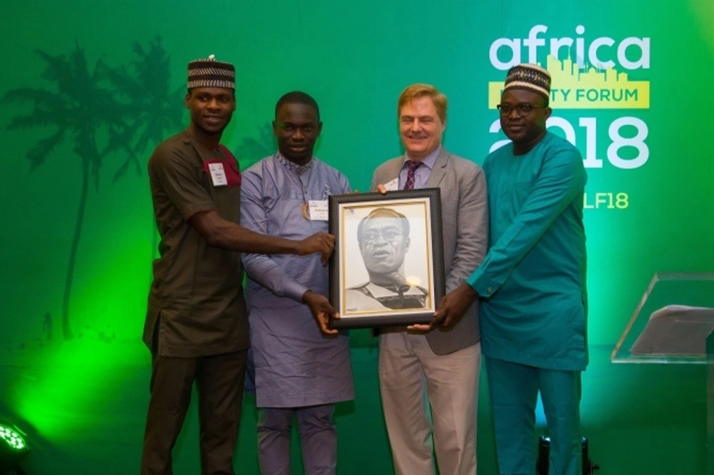 Four men hold a photo of another man at the at the Africa Liberty Forum 2018.