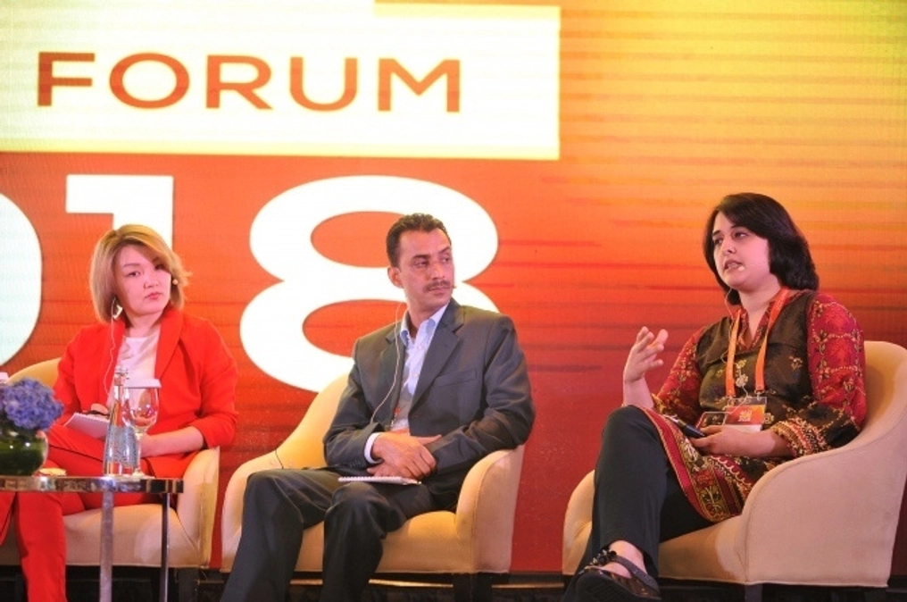 Bilal speaks on a panel at a 2018 forum as other panel members listen.