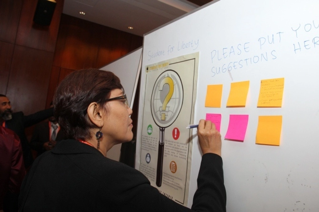 A woman adds thoughts to a sticky note for crowdsourced ideas.