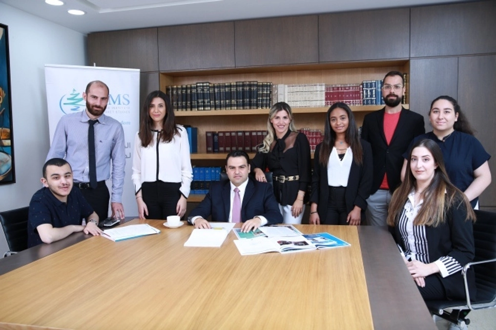 A group in Lebanon poses around a conference table in a. boardroom.