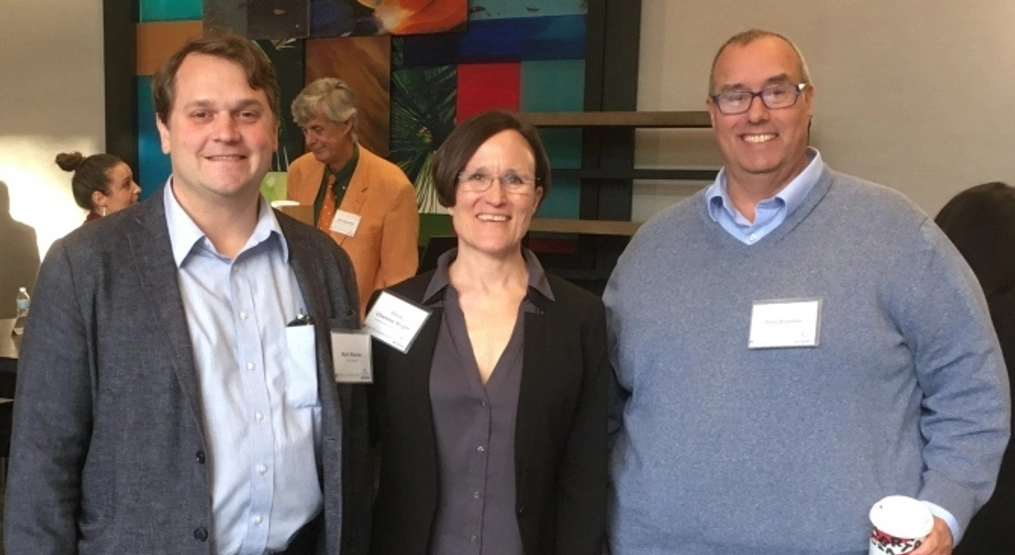 A woman poses for a photo with two men at an Atlas Network event.