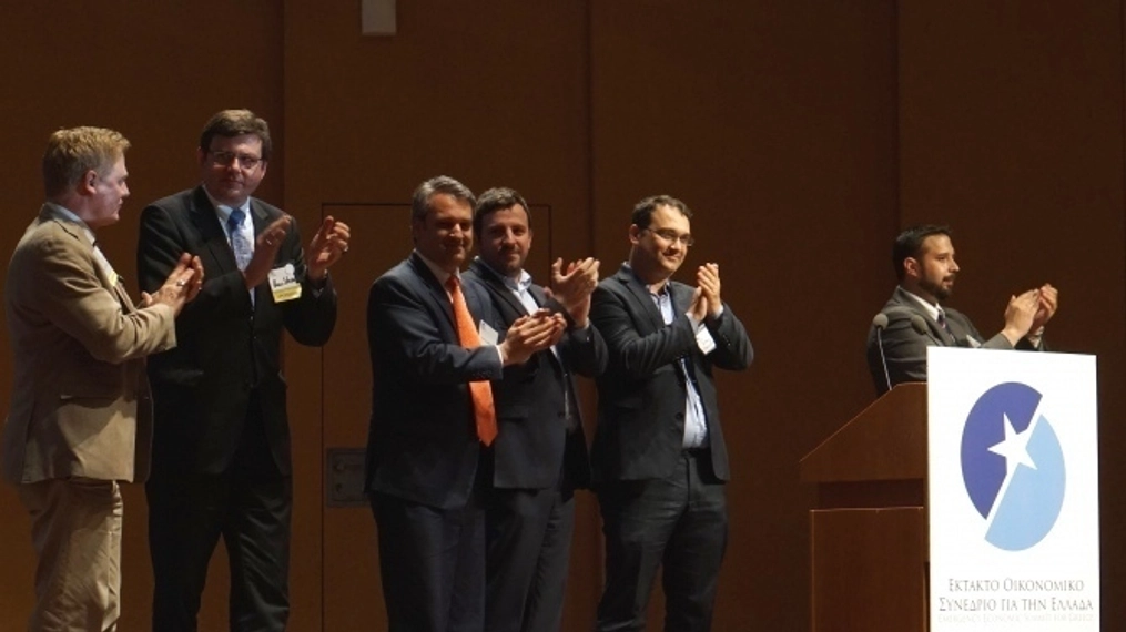 Organizers of emergency econ stand on stage applauding.