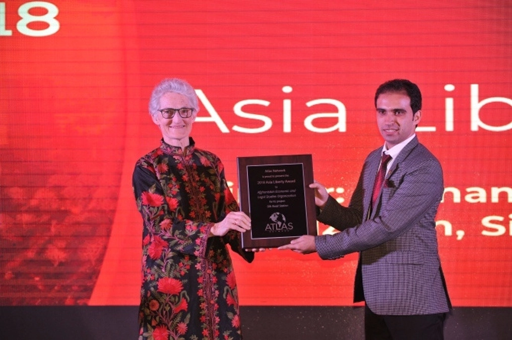 Ramizy holds a plaque on stage at the 2018 Asia Liberty Forum.