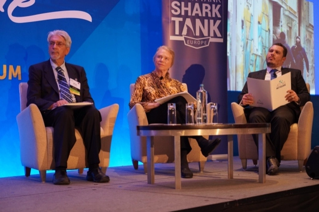 A woman and two men watch intently on stage at the Think Tank Shark Tank.