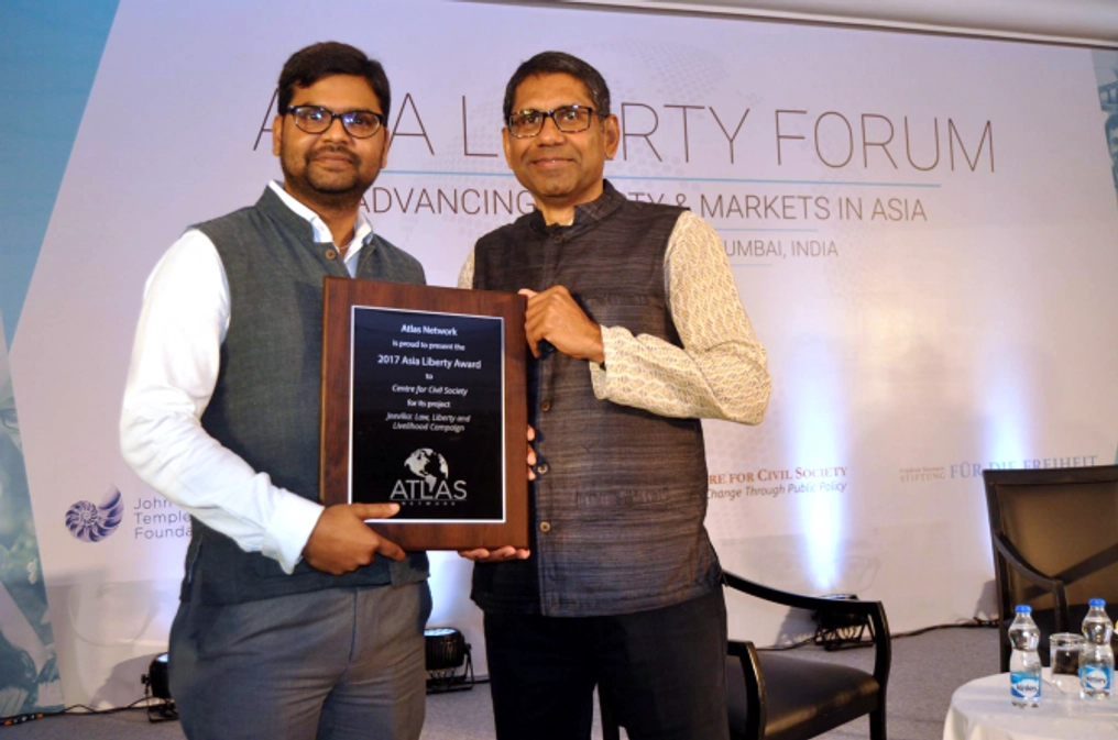 Two men proudly hold a plaque at the Asia Liberty Forum.
