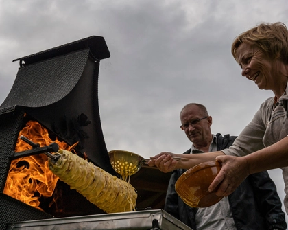 Ona Raudeliūnienė layers batter over a rotating spit during the baking of a traditional šakotis cake (Photo: AtlasNetwork.org/Bernat Parera).