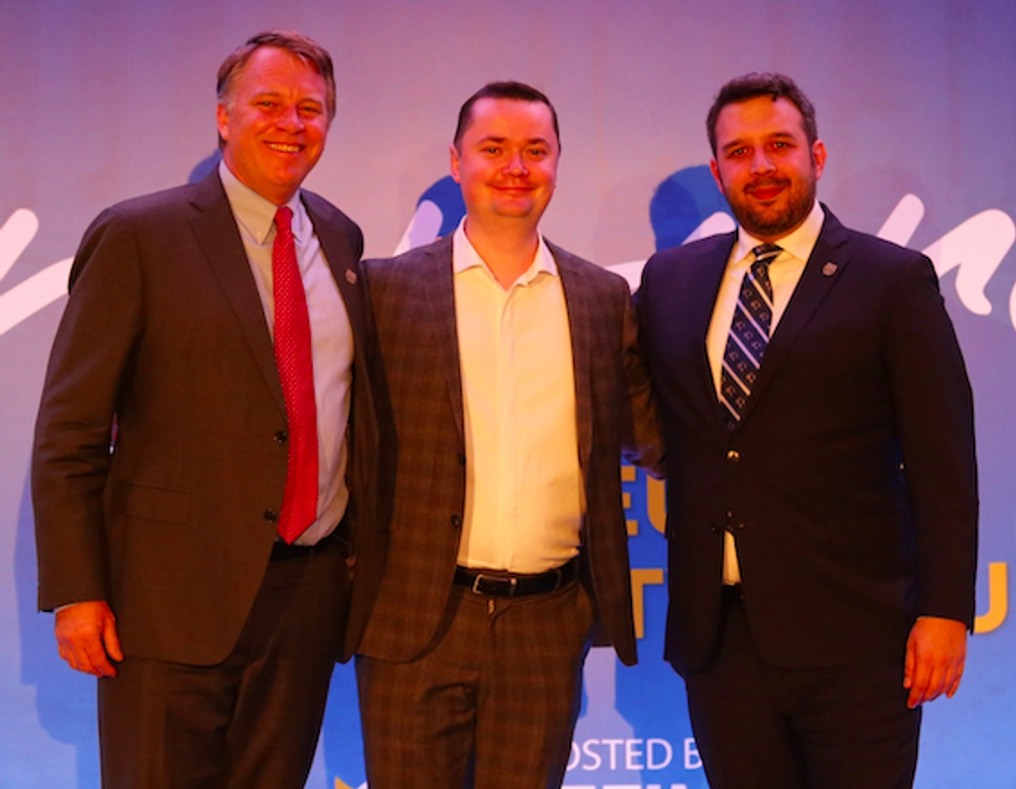 Atlas Network CEO  poses with two men at an event.